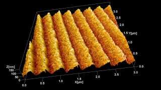 This is a topography image of a holographic, UV optimized, blazed diffraction grating with 2400 lines/mm. It is a good graphic illustration of how much further at the nanoscale Atomic Force Microscopy allows us to ‘see’ beyond what any optical device could. The ridges diffract visible and near-UV light. To light these ridges are perfectly flat. The AFM using a sharp BudgetSensors tip shows us that their surface is actually quite rough.
これは、2400 本/mm のホログラフィック、UV 最適化したブレーズ回折格子の表面形状像です。ナノスケールの原子間力顕微鏡によって、光学デバイスの限界を超えてどれほど拡大して「見る」ことができるかを示す良い例です。リッジは可視光と近紫外光を回折します。光学的にはこれらの尾根は完全に平坦ですが、 BudgetSensors の鋭い探針を使用した AFM では、その表面が実際にはかなり粗いことがわかります。